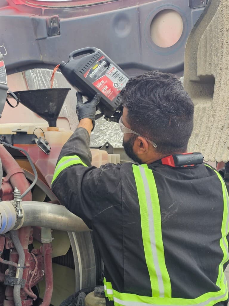 Hub Transport technician pouring coolant during commercial truck maintenance