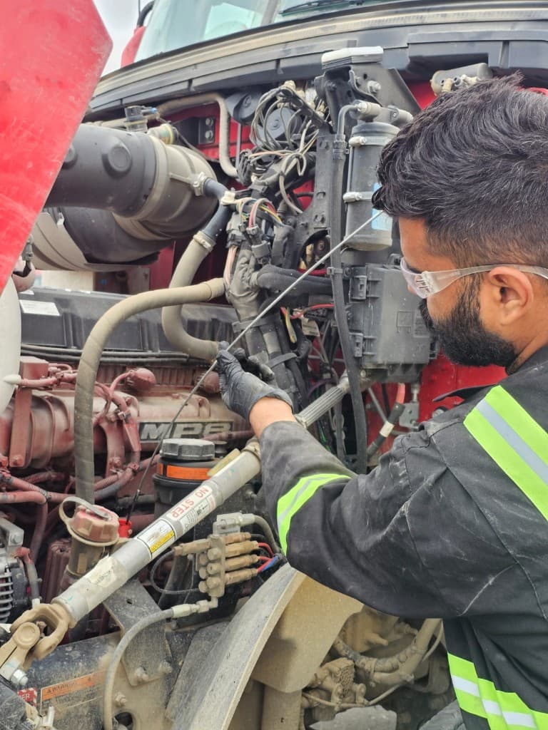 Hub Transport technician checking fluid levels on a commercial truck engine