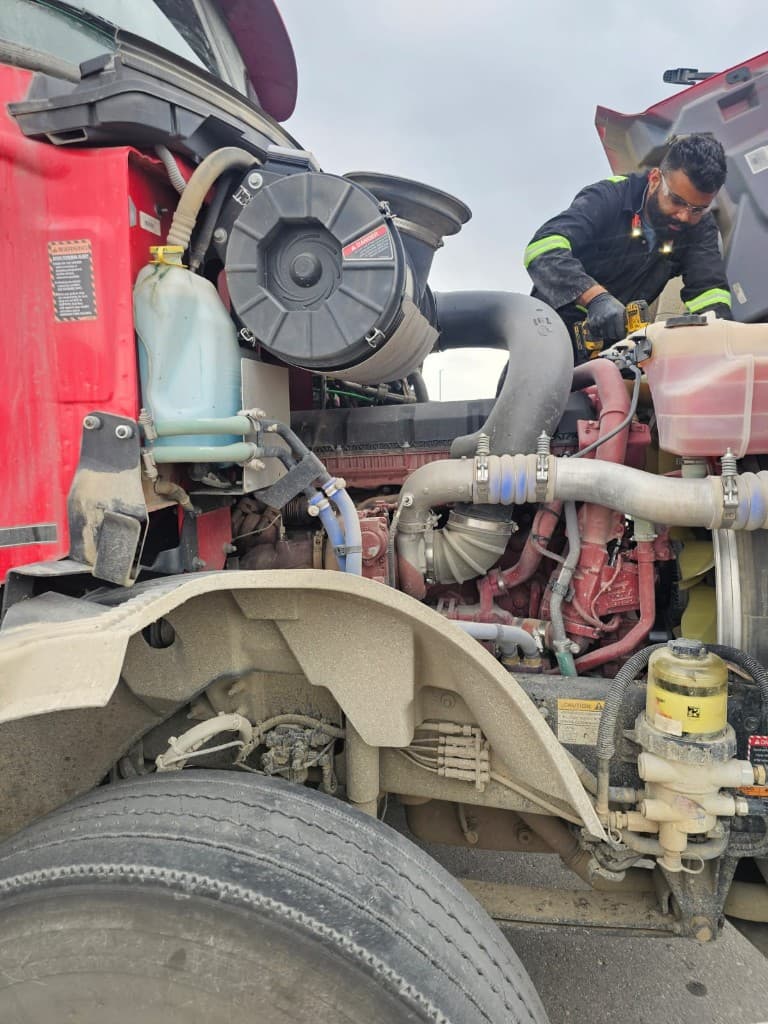 Hub Transport technician working on a commercial truck engine during a maintenance check