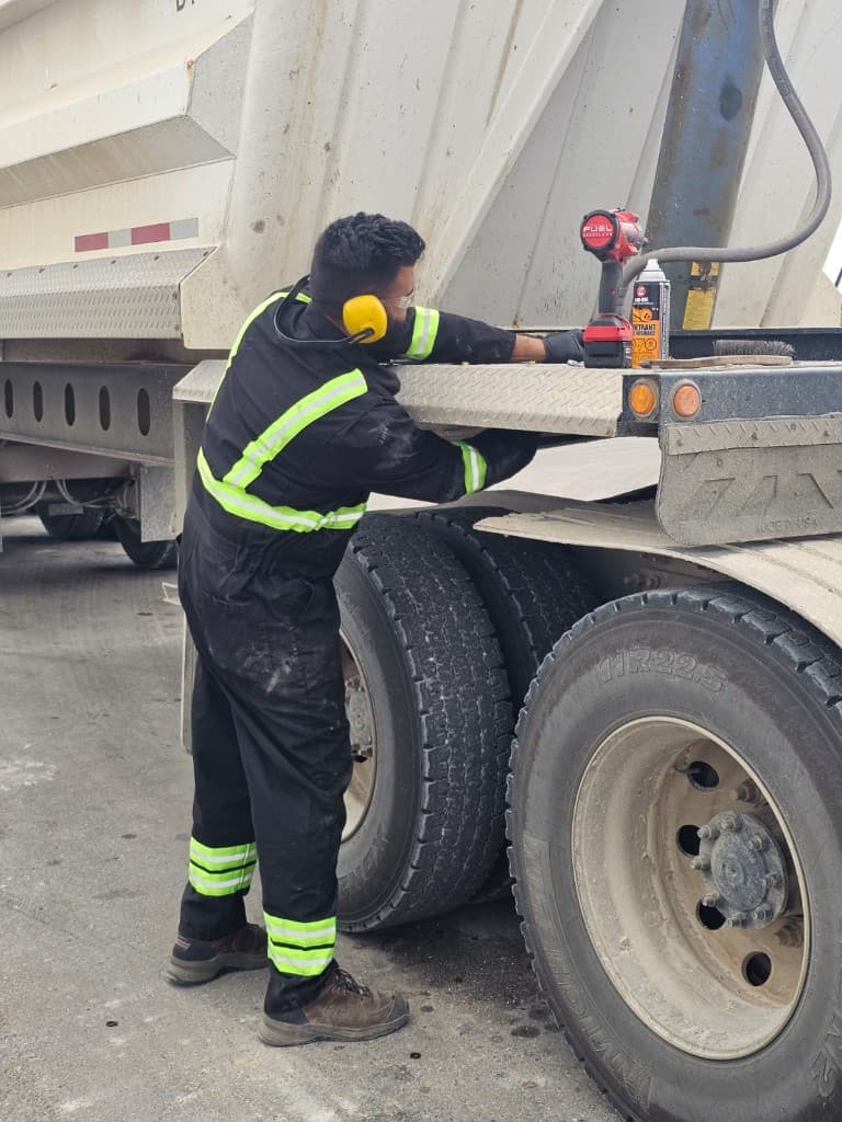 Hub Transport technician performing trailer maintenance with power tools on site