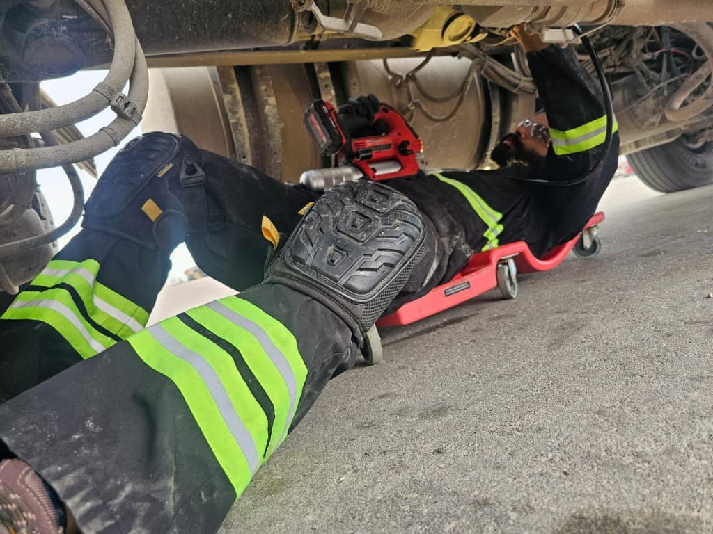 Hub Transport technician performing undercarriage maintenance on a commercial truck
